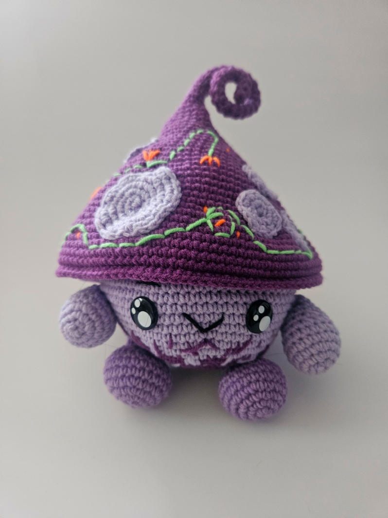 Product Description: Materials used: Yarn, Polyfil, Safety Eyes</br></br>Dimensions: 6wx8hx5d inches</br>Cute amigurumi character. Unique gift for family and pets.</br></br>Artist Statement: Crochet is one of my favorite mediums for artistic expression, where yarn and a hook become the tools through which I craft whimsical characters and imaginative worlds. With each stitch, life is given to these soft sculptures, transforming simple materials into endearing creatures. My work in Amigurumi crochet is a testament to the power of handmade artistry, as each piece has their own unique personality and charm. Through this craft, I seek a sense of wonder, joy, and nostalgia in those who encounter my creations, inviting them to embrace the magic of the handmade and the infinite possibilities of yarn.</br></br>Bio: Casey Lucas is a versatile artist with a background in both dance and visual arts. She earned her Bachelor of Fine Arts (BFA) in Dance from Mason Gross School of the Arts and a Master of Fine Arts (MFA) in Art - Ceramics from Kean University. Casey's artistic journey spans various creative mediums, including Amigurumi crochet and ceramics, through which she brings her unique vision to life. After living in New York City for over a decade, she currently resides in the picturesque town of Princeton, New Jersey. Casey shares her life with her husband and two children, drawing inspiration from the town's historic charm. Her work beautifully combines the tactile and visual arts, creating a seamless fusion of movement, texture, and form. Whether through the fluidity of dance or the intricacies of crochet and ceramics, Casey's artistry is a testament to her unwavering commitment to the creative process. Beyond her artistic pursuits, Casey is a recent breast cancer survivor, showcasing incredible resilience and strength throughout her personal journey. She has chosen to use her art as a force for good, dedicating a portion of her sales to support cancer research. Her work not only embodies creativity and passion but also carries a profound message of hope and determination.</br></br>$40 *</br>Price subject to sales tax.</br></br>Item Number: CL53</br> Amigurumi Mushroom Gnome by Casey Lucas
